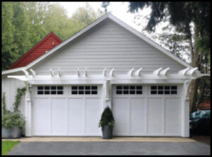 White double garage doors with small grid windows along top, on white home.