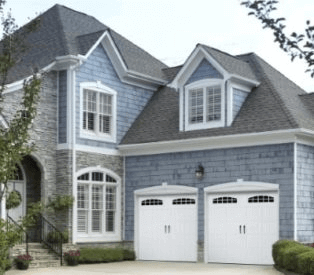 Large home with blue shingle siding and attached double garage with white garage doors.