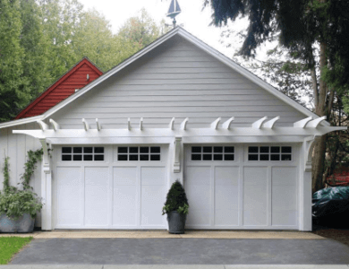 White double garage doors with small grid windows along top, on white home.