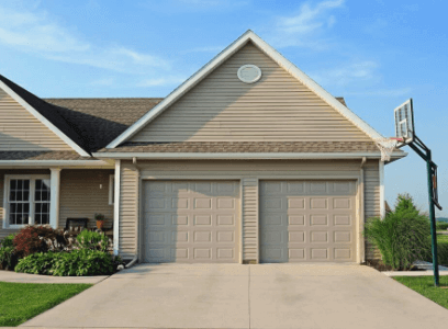 tan double garage doors on house with tan siding and light brick