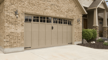 Large tan garage door with small windows at the top, in a tan brick home.