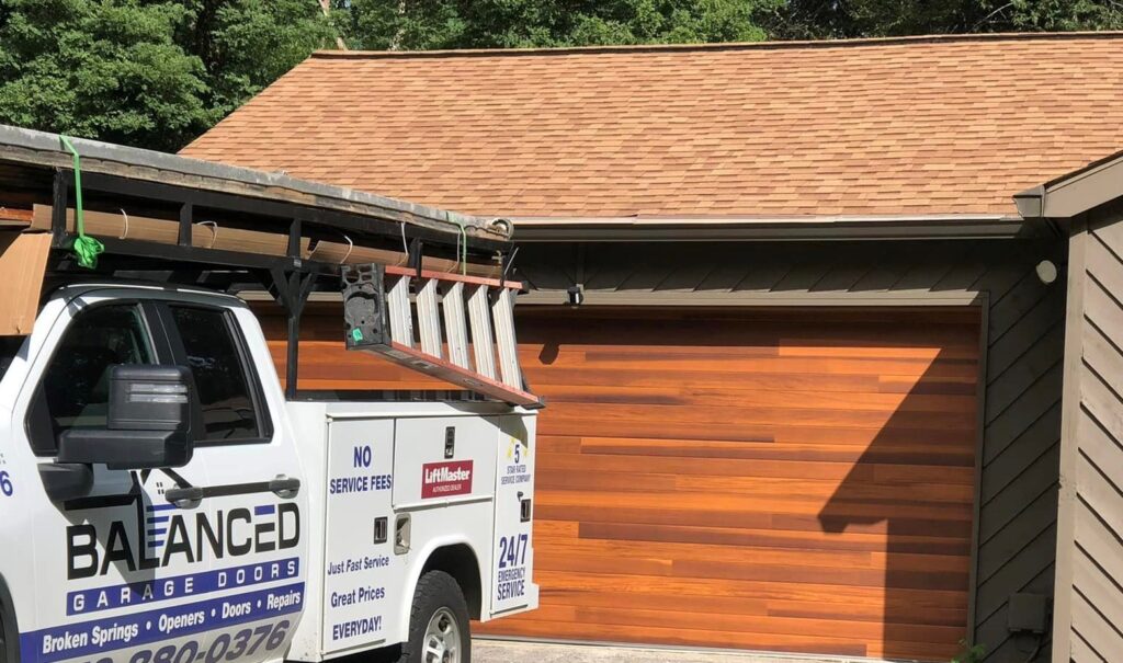 Balanced Garage Doors truck sitting outside home with newly installed wood garage door