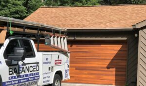 Balanced Garage Doors truck sitting outside home with newly installed woodgrain garage door.