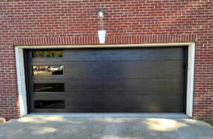 newly installed modern black garage door on a brick house