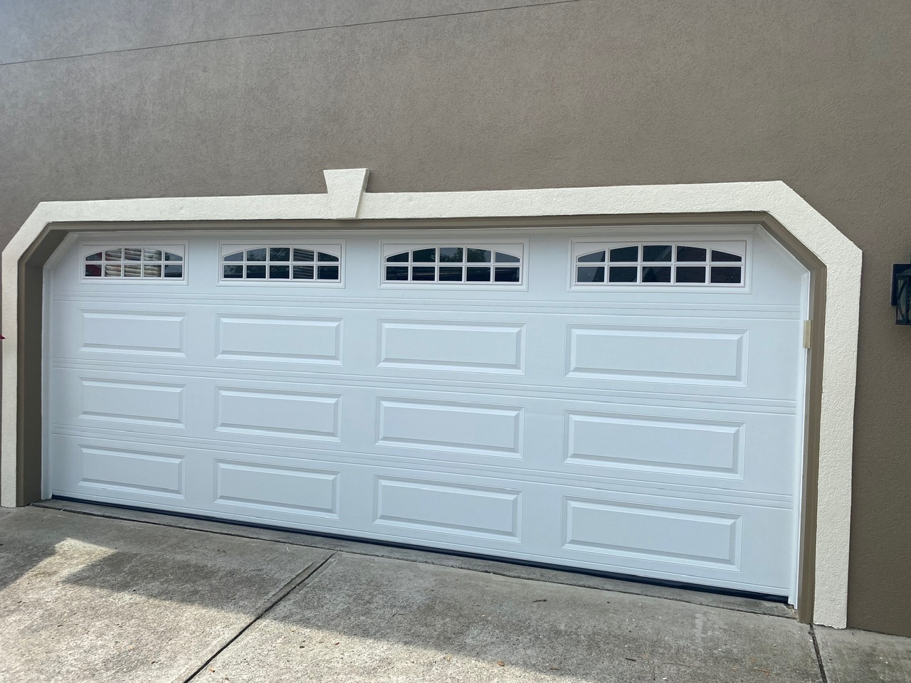 White raised-panel traditional garage door with small windows across the top